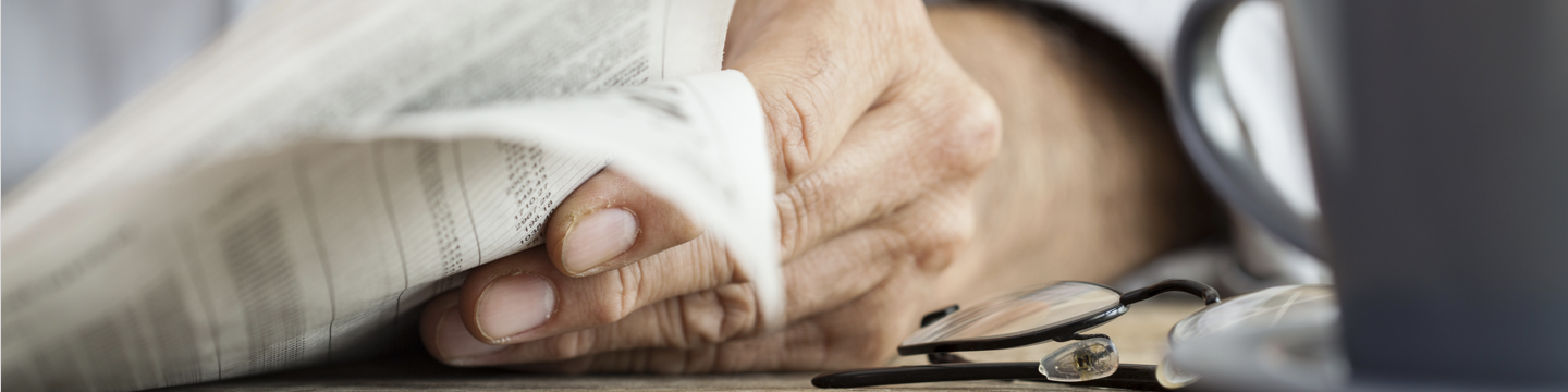 Hand blättert Zeitung um